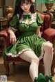 A woman in a green dress sitting on a red chair.