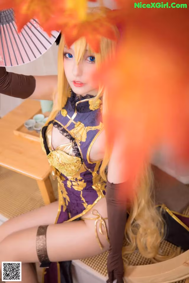 A woman in a purple and gold outfit holding a fan.