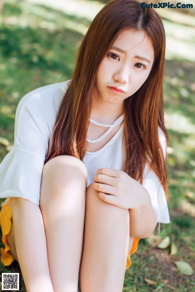 A woman sitting on the ground with her legs crossed.