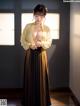 A woman in a yellow and black kimono standing in a room.