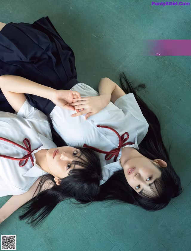 A couple of girls laying on top of a green floor.