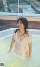 A woman in a white shirt is sitting in a hot tub.