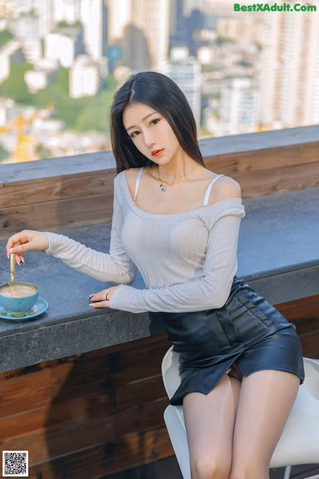 A woman sitting at a table with a cup of coffee.