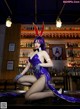 A woman in a bunny costume sitting on a bar.