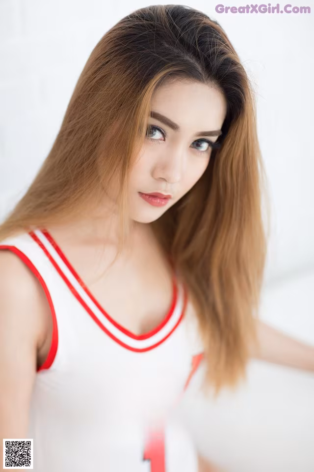 A woman in a white and red basketball jersey posing for a picture.