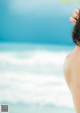 A woman standing on the beach with her back to the camera.