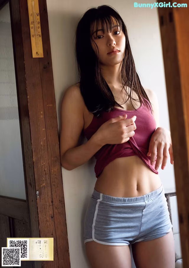 A woman in a pink top and blue shorts posing for a picture.
