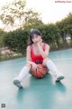 A woman sitting on a basketball court holding a basketball.