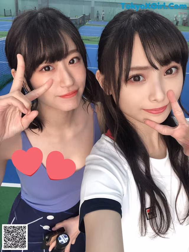 Two young women posing for a picture on a tennis court.