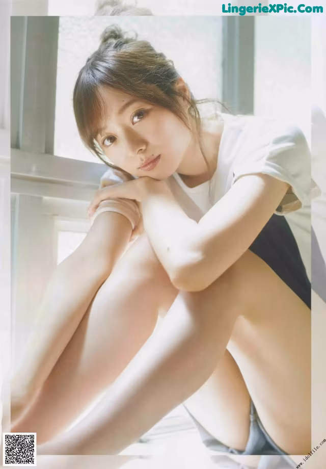 A woman sitting on a window sill with her legs crossed.
