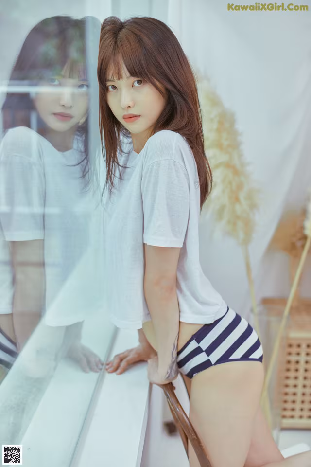 A woman in a white shirt and blue and white striped shorts.