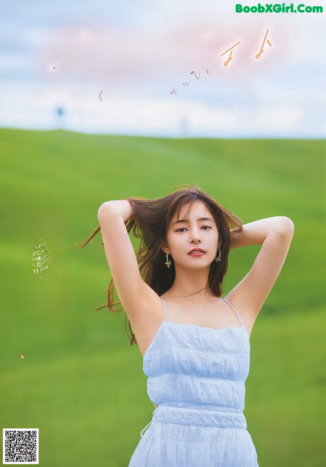 A woman in a blue dress standing in a green field.