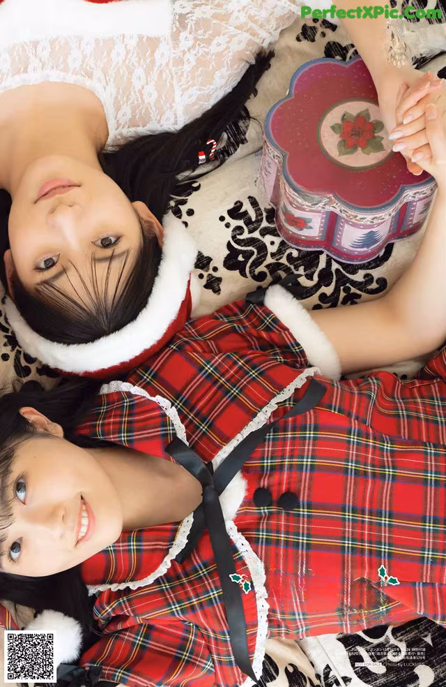 A couple of women laying on top of a bed.