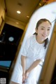 A woman in a white dress standing in front of a mirror.