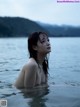 A naked woman standing in a body of water.